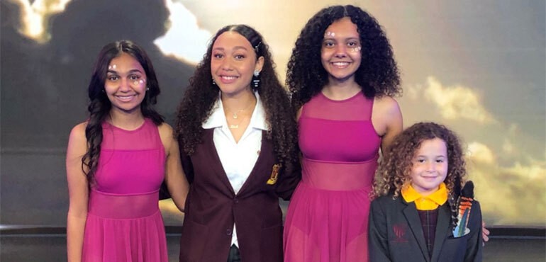 Four female students smiling and looking forward.